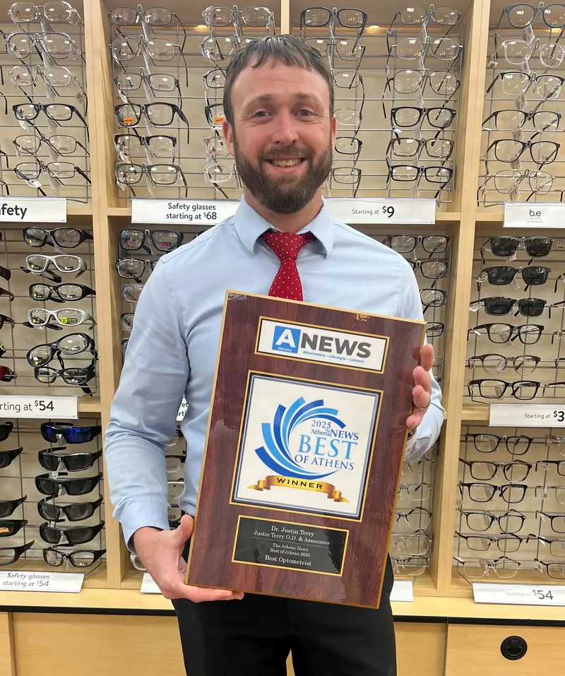 Dr. Justin Terry in the Vision Center, smiling and holding his Best of Athens 2025 plaque for Best Optometrist